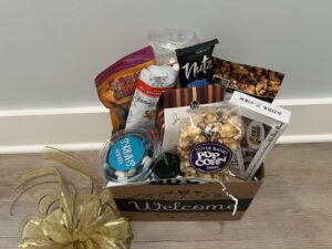 A warm colored basket saying welcome filled with snacks 