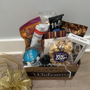 A warm colored basket saying welcome filled with snacks